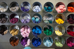 bins containing colorful skeins of yarn line the wall of yarnology, a specialty shop in winona