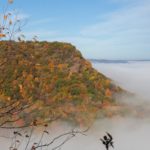 Winona bluffs with fall colors rise above clouds