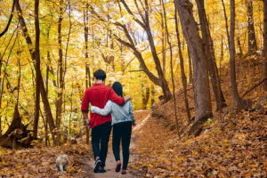 couple walking dog on bright yellow fall hiking trail in Winona