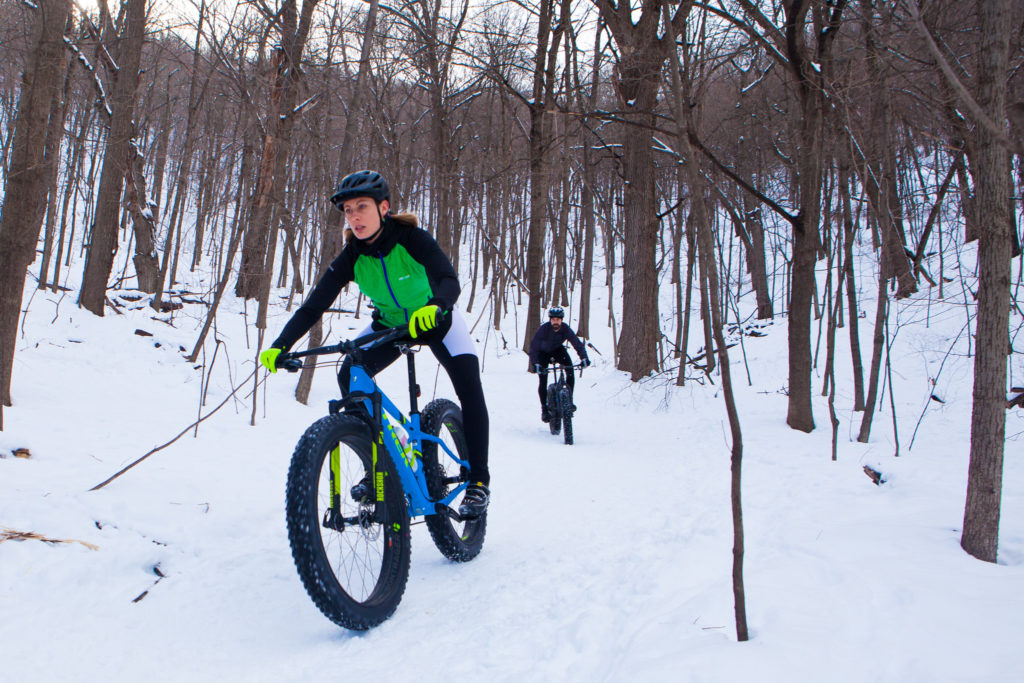 two bicyclists on fat tire bikes pedal on snowy bluff trails around Winona